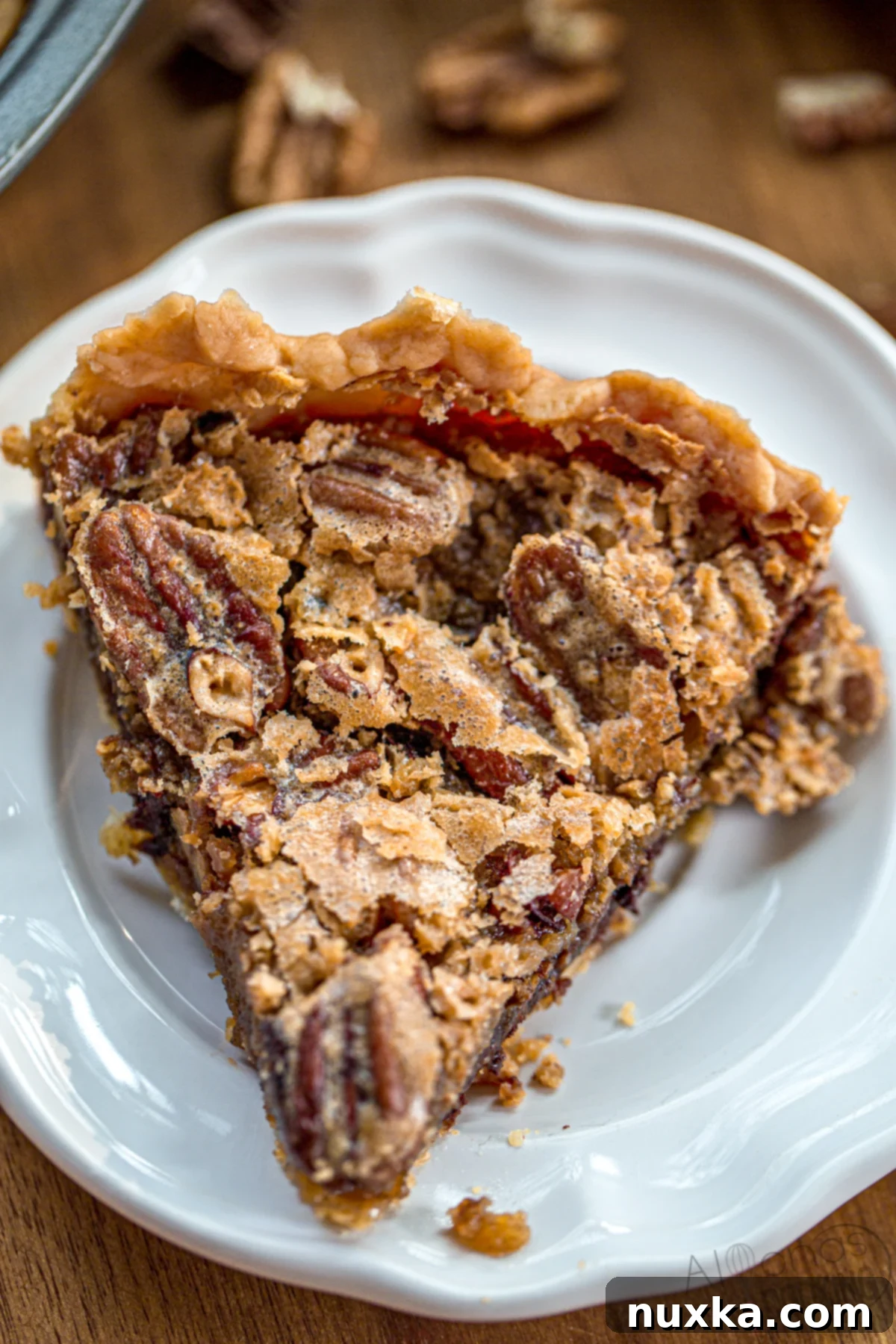 slice of homemade pecan pie with a perfectly gooey filling, topped with pecans