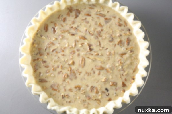 pecan pie filling in pie crust before baking pecan pie with filling in the crust, ready to go into the oven