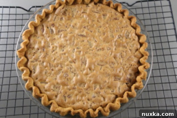 baked pecan pie baked pecan pie, golden brown with pecans on top, cooling on a rack