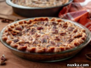 pecan pie in pie pan after baking, with pecan halves on top