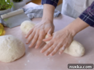 Rolling out Italian bread loaves by hand to make oval loaves