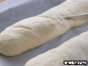 slashing Italian bread loaves with a sharp knife diagonally
