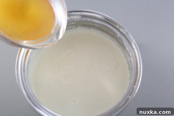 Adding the remaining chicken broth to the smooth cream cheese sauce