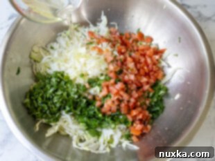 cabbage salad ingredients in a large bowl being poured with a homemade vinaigrette