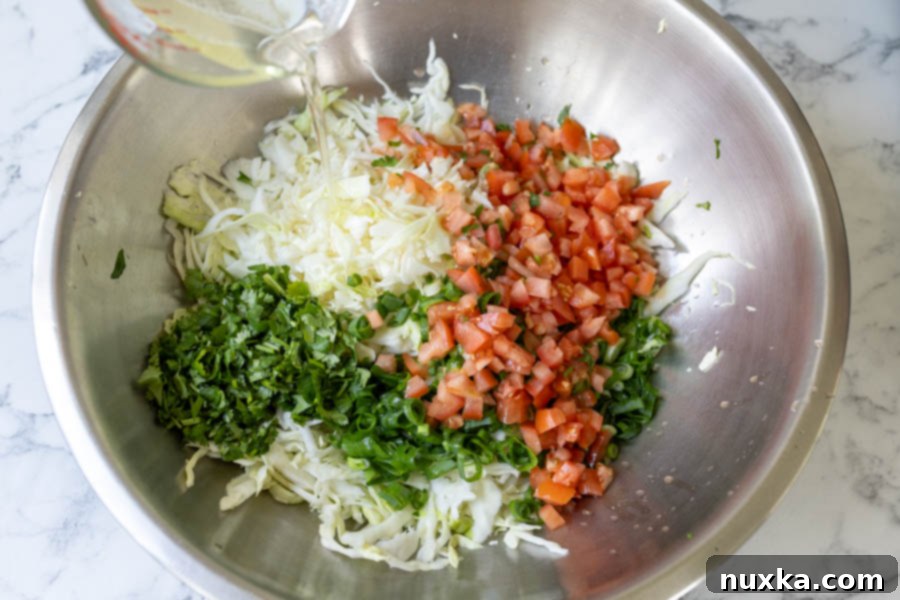 cabbage salad in a large bowl being poured with a homemade vinaigrette 