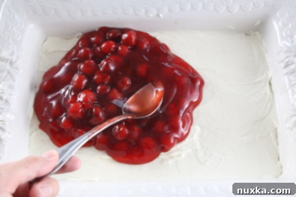 Finished Cherry Pretzel Cheesecake Dessert in a baking dish before chilling, showcasing all layers.