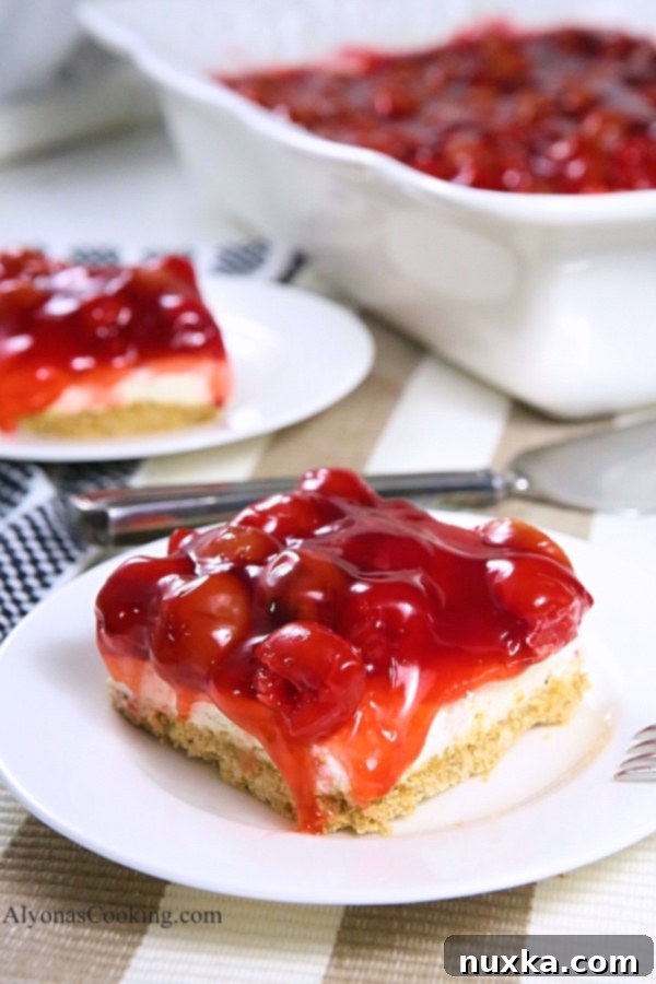 Two slices of Cherry Pretzel Cheesecake Dessert on a white plate, ready for serving.