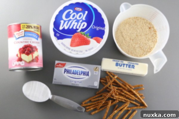 Ingredients for Cherry Pretzel Cheesecake: melted butter, crushed pretzels, graham cracker crumbs, and sugar in bowls.
