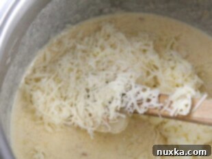Adding cheese to the simmering sun-dried tomato cream sauce.