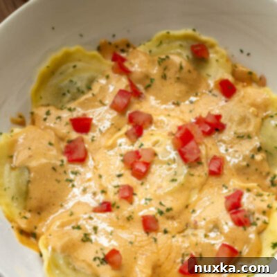 A beautifully plated serving of Olive Garden's mushroom ravioli copycat recipe, garnished with diced tomatoes and dried parsley.