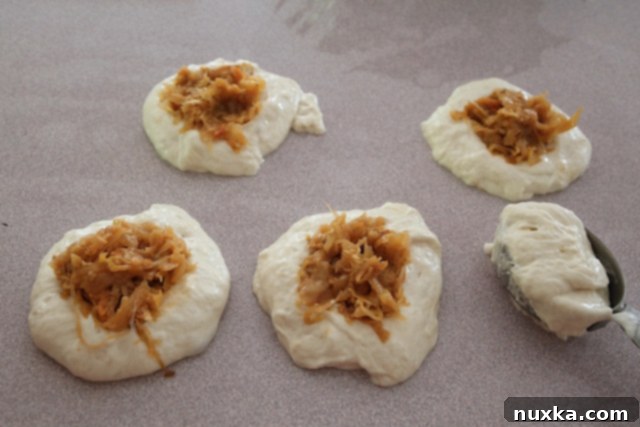 Adding savory cabbage filling to the center of the belyashi dough