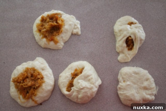 Skillfully sealing the belyashi dough around the cabbage filling
