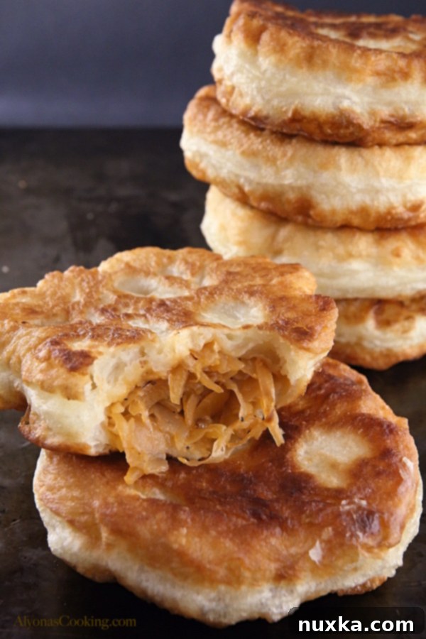 A plate full of freshly fried, golden cabbage belyashi