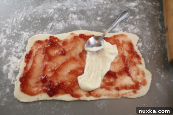 Raspberry jam and cream cheese spread on Rugelach dough, ready for rolling.