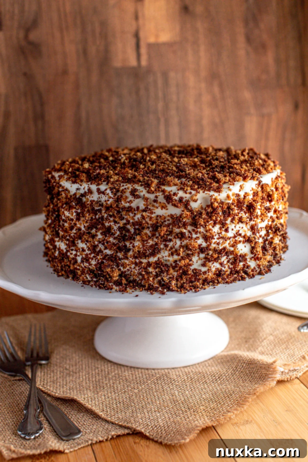 Russian Sour Cream Cake Recipe called Smetannik Cake, garnished with crumbs.