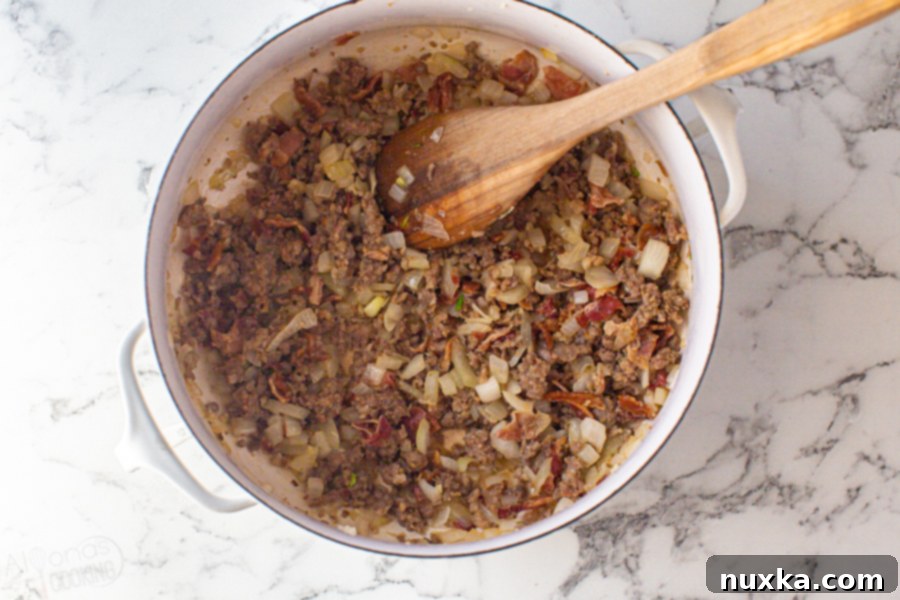 Step-by-step image 1: Frying diced onion, ground Italian sausage, chopped bacon, and crushed garlic in a large pot, forming the aromatic base of the Zuppa Toscana.