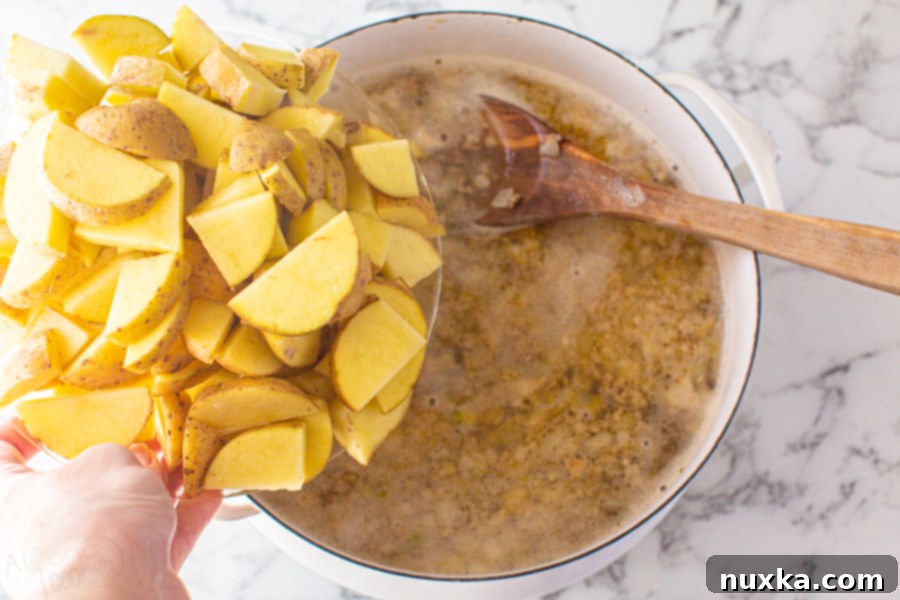 Step-by-step image 2: Diced potatoes are added to the pot with water, salt, and chicken bouillon, simmering for 25 minutes until tender, absorbing all the flavors.