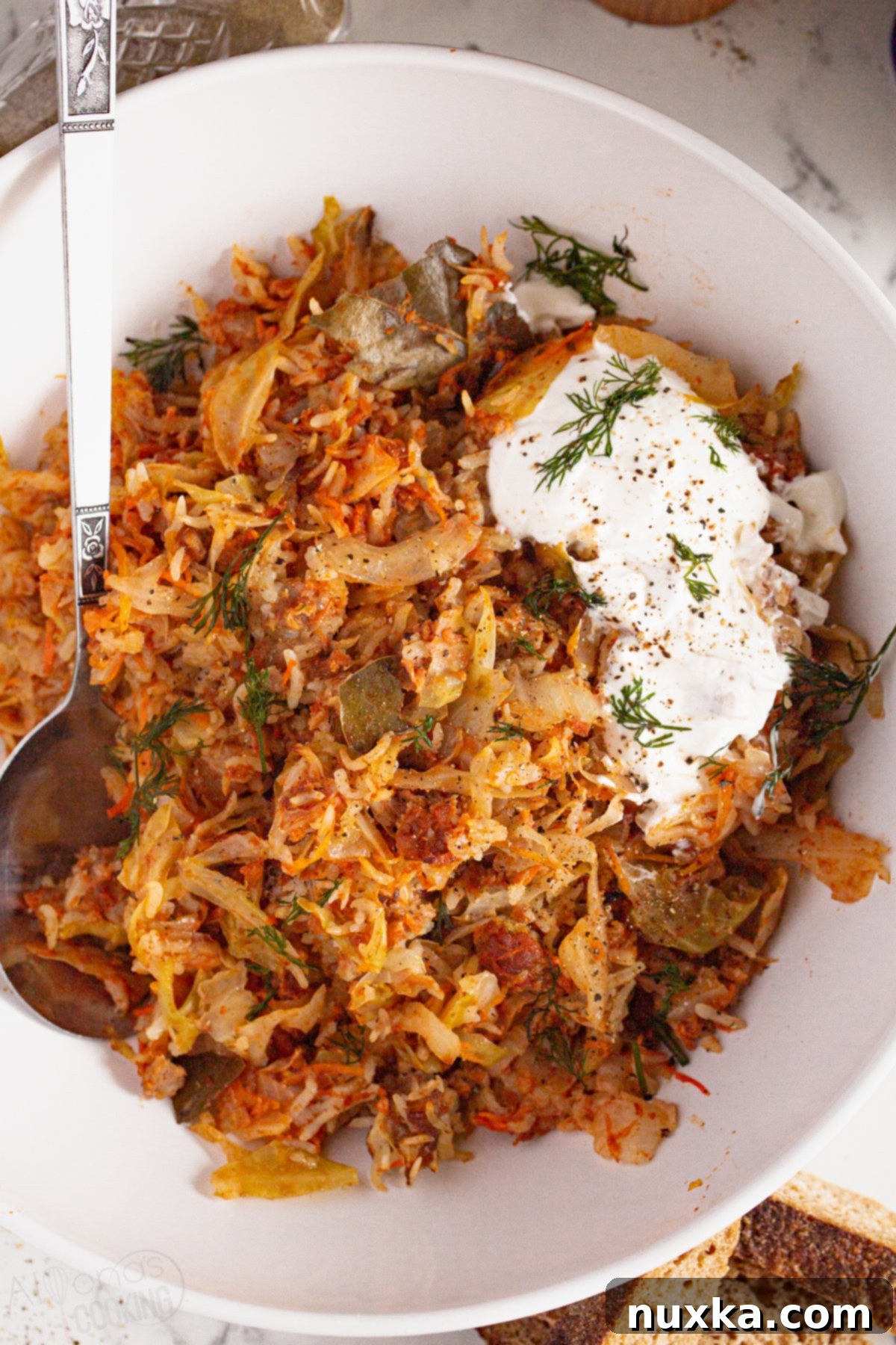 image of unstuffed cabbage rolls on a plate with sour cream and dill