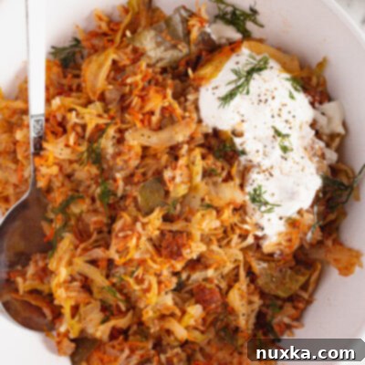 Effortless Cabbage Casserole 2 image of unstuffed cabbage rolls on a plate with sour cream and dill
