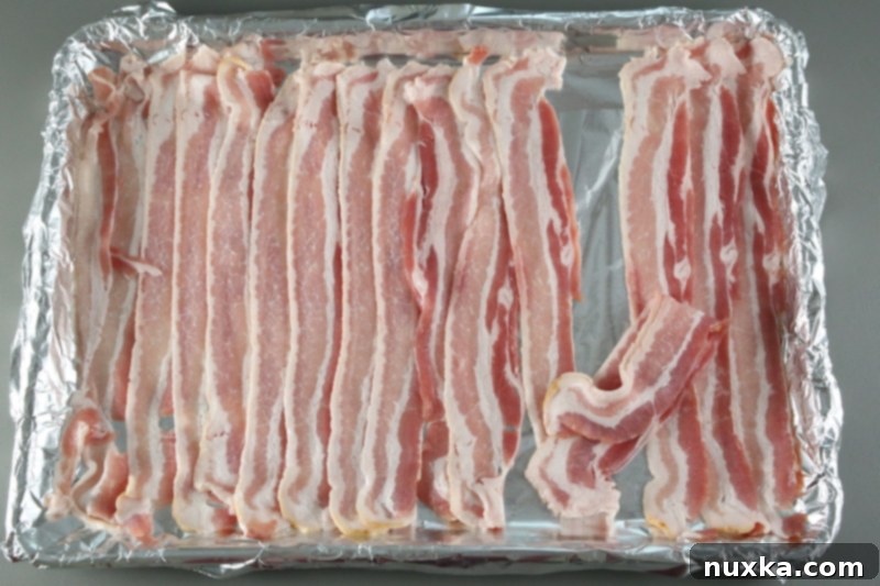 arranging bacon slices on a rimmed baking sheet to bake in the oven