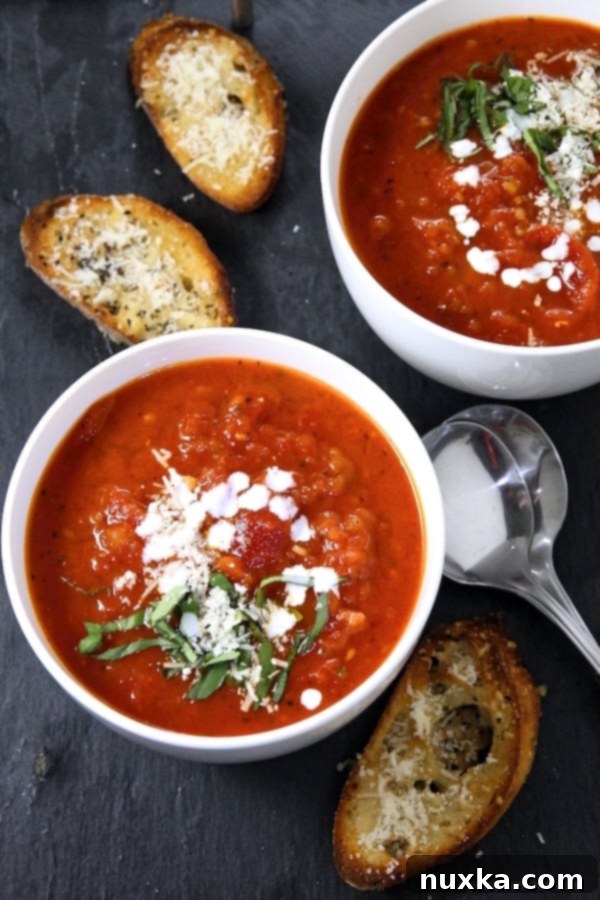Delicious creamy homemade tomato soup garnished with basil and parmesan, ready to be served