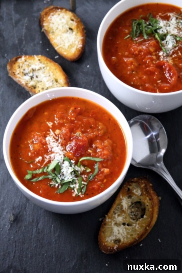 Bowl of finished easy tomato soup garnished with parmesan cheese and basil