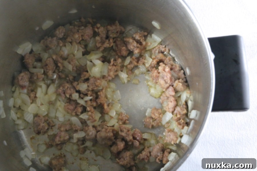 Sautéing onions and crumbled Italian sausage in a large pot