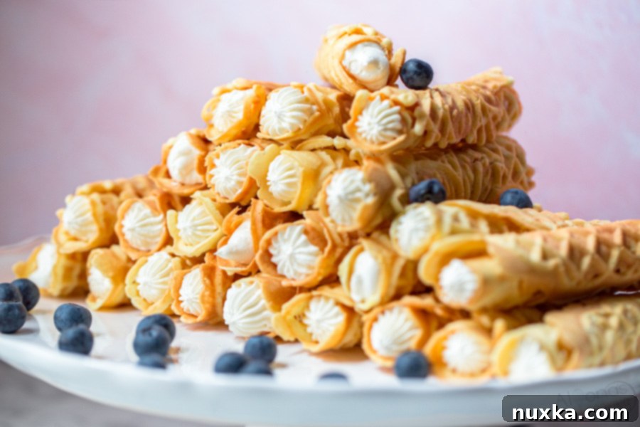 cream filled Pizzelles on a cake stand with blueberries