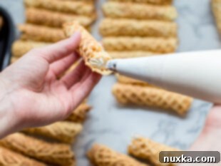 piping cream into rolled Pizzelles