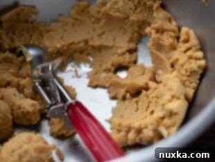 Peanut butter cookie dough batter inside a stainless steel mixing bowl, ready for baking