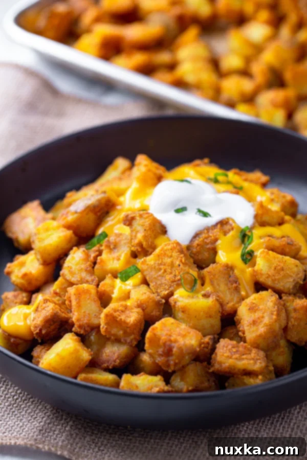 taco bell cheesy fiesta potatoes with sour cream in a black bowl