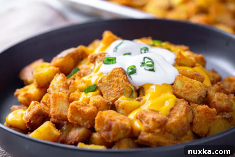 taco bell cheesy fiesta potatoes with sour cream and cheese on a black plate and green onions