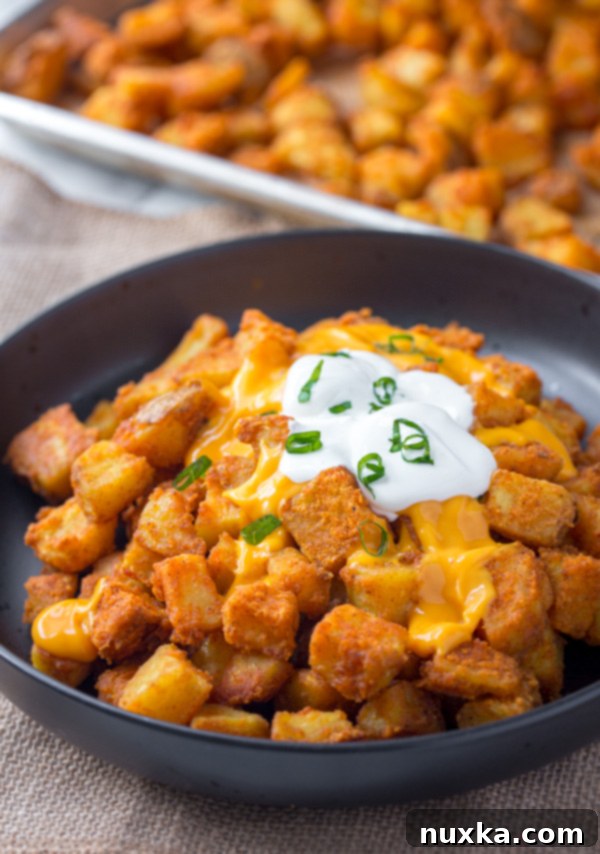 taco bells cheesy fiesta potatoes with sour cream and cheese on a black plate and green onions