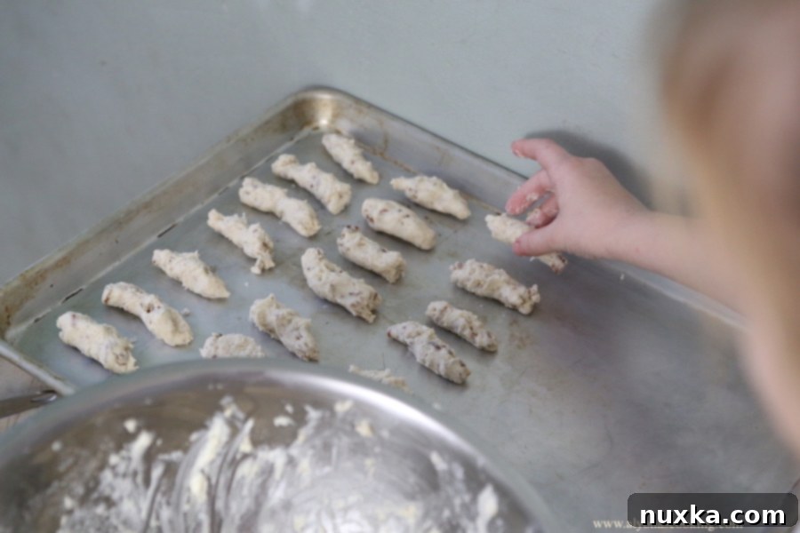Several Nutty Fingers cookies arranged neatly in a line, highlighting their uniform size and perfect powdered sugar coating.