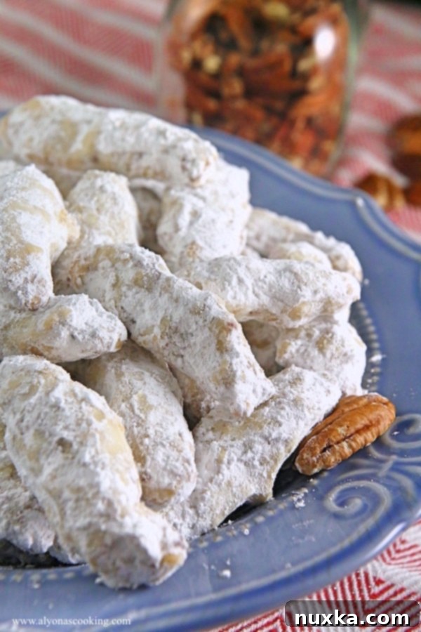 A bowl filled with crunchy Nutty Fingers cookies, coated in a generous layer of powdered sugar, with some ready to be picked up for a snack.