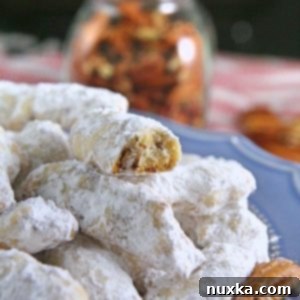 Crunchy Nutty Fingers cookies coated in powdered sugar, stacked neatly on a plate.