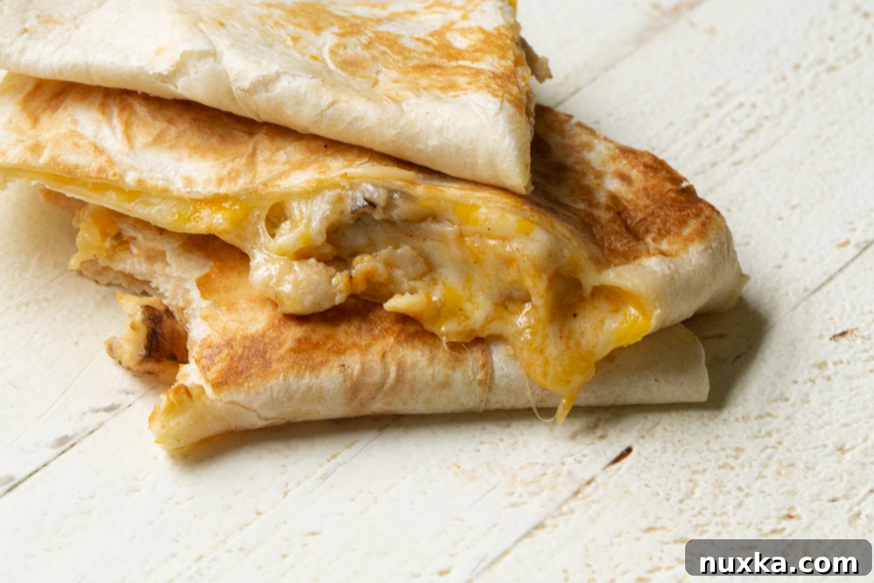 A serving of cheesy chicken quesadillas, reminiscent of Taco Bell's, with a side of creamy quesadilla sauce for dipping.
