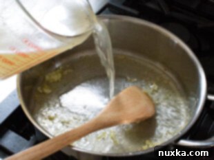 adding chicken broth to the pan for angel hair pasta