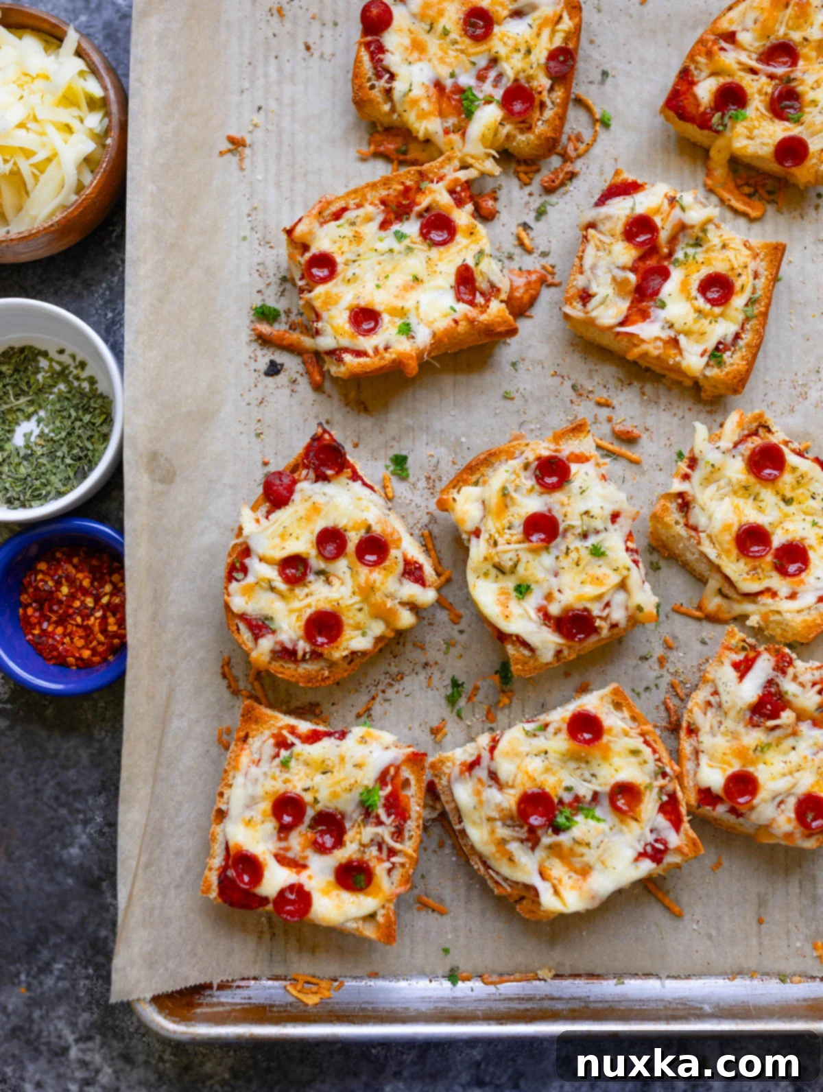 Freshly baked French bread pizzas with pepperoni and melted cheese on a baking sheet