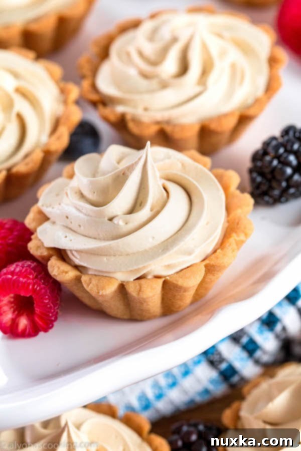 Close-up of baked mini tart shells, showcasing their perfect basket shape and golden-brown shortbread texture.
