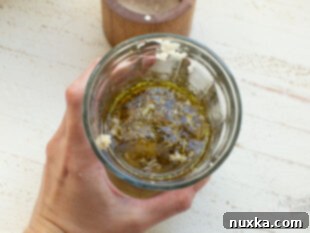 Adding spices and crushed garlic to olive oil in a container