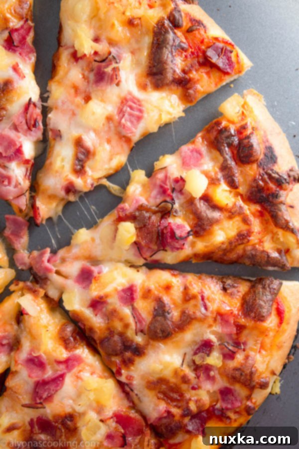 A slice of Hawaiian pizza being lifted