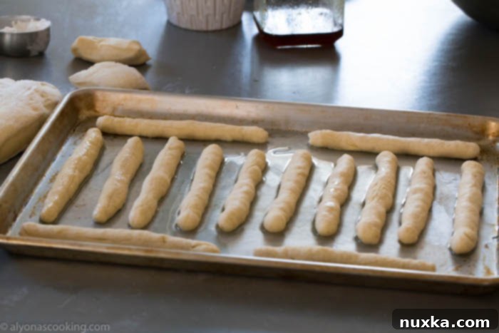 Breadsticks rising on a baking sheet before going into the oven