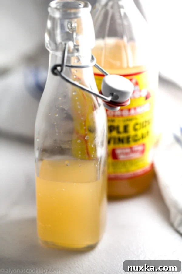 apple cider vinegar, the best rice vinegar substitute, shown in a glass bottle with fresh ingredients in the background