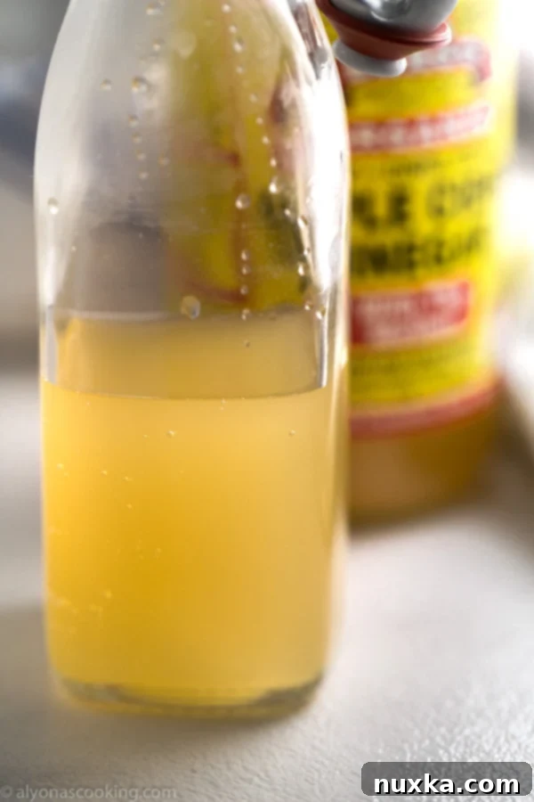 Various types of vinegar bottles on a wooden surface, including apple cider vinegar, symbolizing substitution options for rice vinegar.