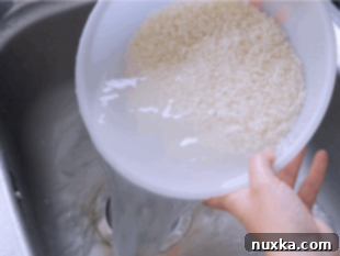 Rinsing short-grain sushi rice in a sieve to remove excess starch.