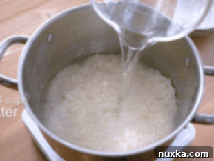 Cooking rinsed sushi rice with cold water in a pot on the stove.