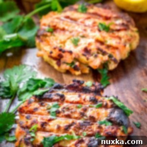A delicious salmon burger patty on a bun, topped with fresh greens and a creamy sauce.