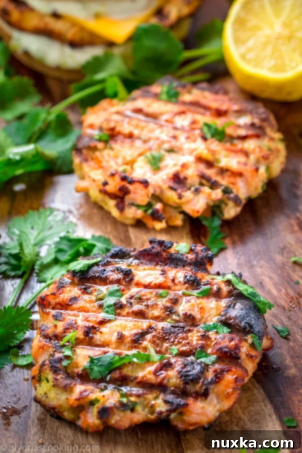 A top-down view of a fully assembled salmon burger on a plate, with a soft bun, a juicy patty, and fresh toppings.