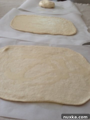Pizza dough rising on parchment paper before grilling
